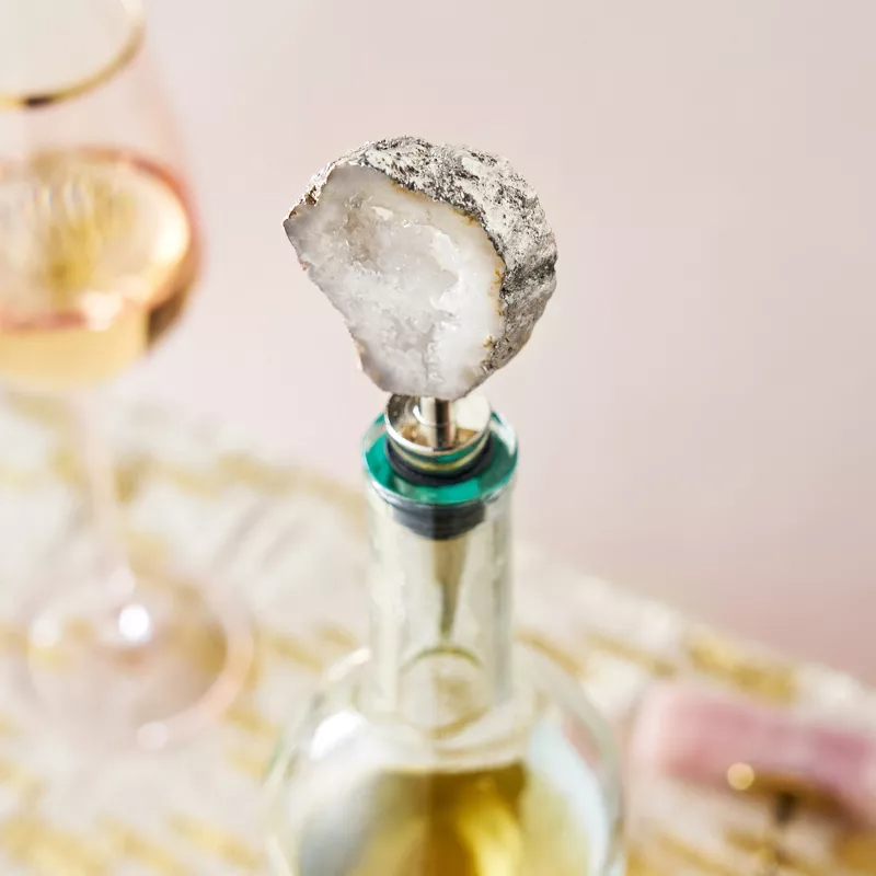 Wine bottle with a crystal stopper on a table, next to a filled wine glass