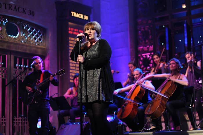 A singer performs on a stage with a band and string ensemble