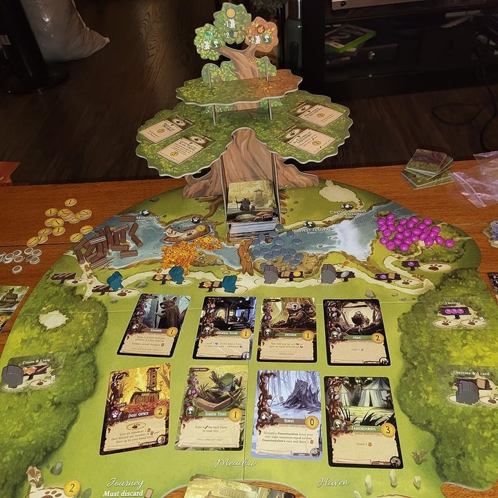 Board game setup featuring a tree-shaped game board with cards, tokens, and various game pieces arranged for play