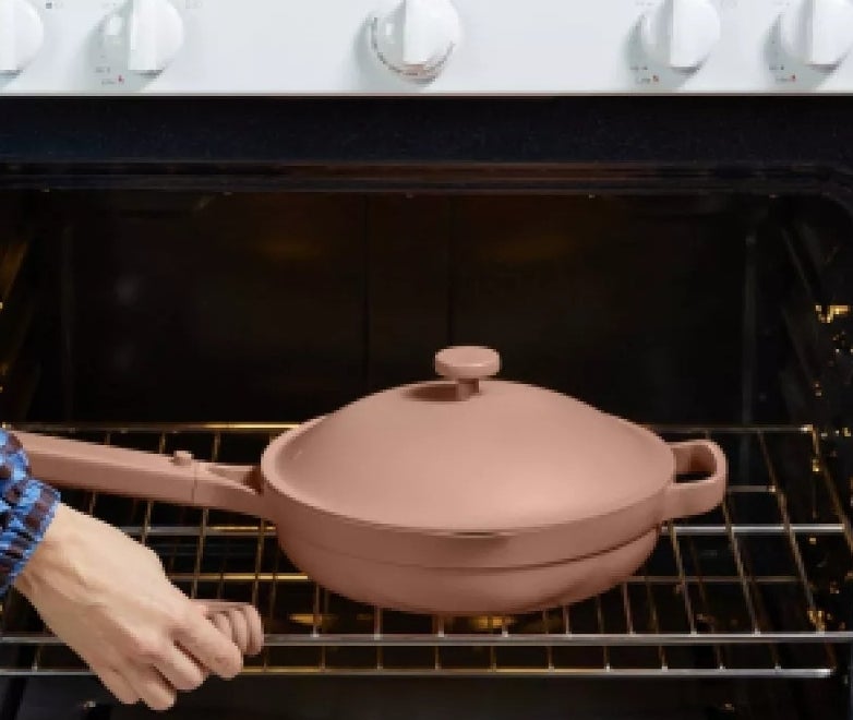 A person places a lidded skillet into an oven