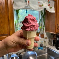 A hand holds a cone of bright pink ice cream