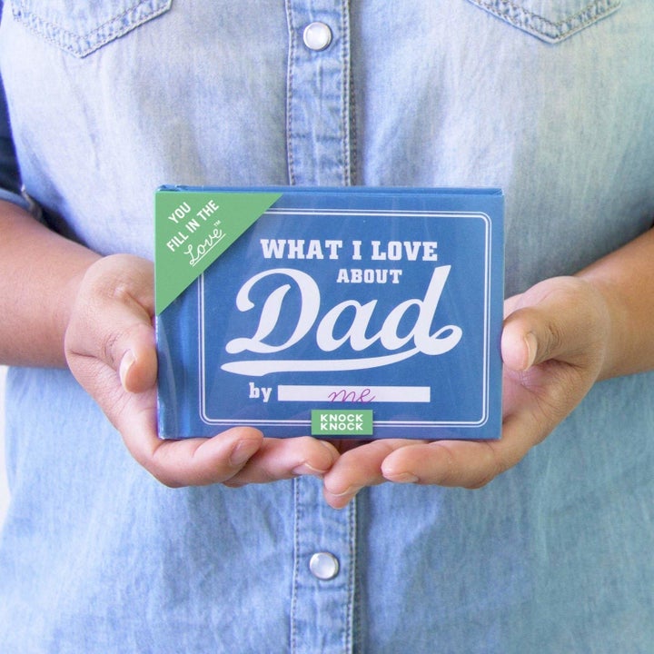 Person holding a "What I Love About Dad" book with a space to fill in personal thoughts