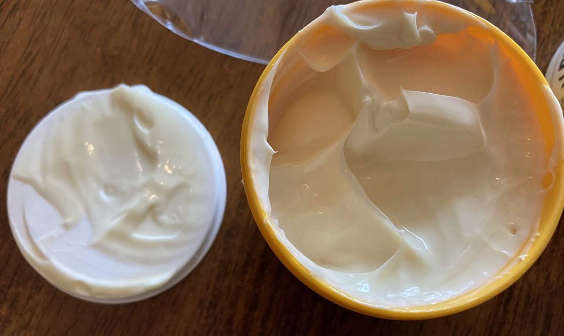 Open jar and lid with creamy substance on a wooden surface