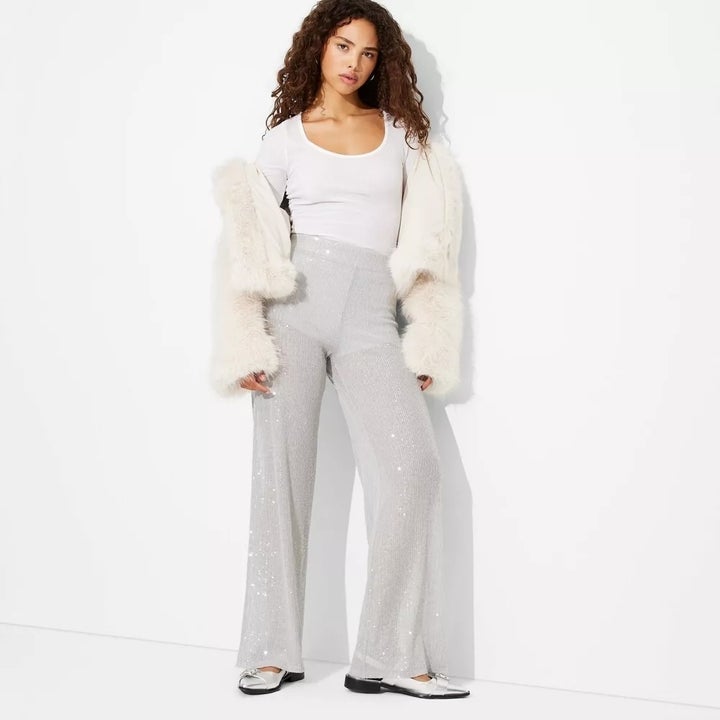 Model with white top, grey sequin pants and white fur jacket