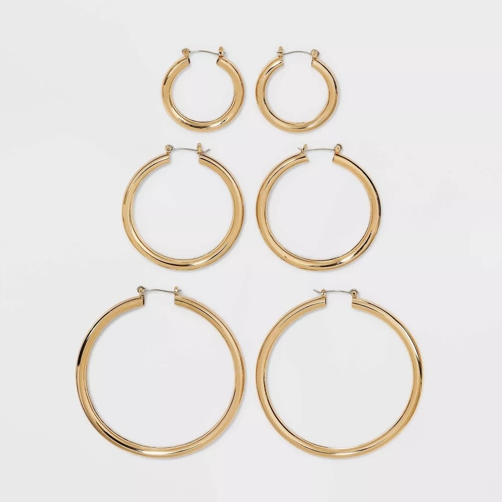 Six pairs of gold hoop earrings in varying sizes displayed on a plain background