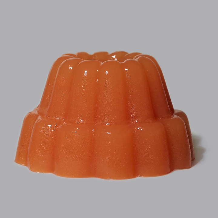 A single orange jelly dessert with a fluted mold shape