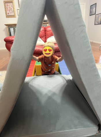 Toddler playing successful a soft, foldable playhouse operation indoors, surrounded by colorful toys
