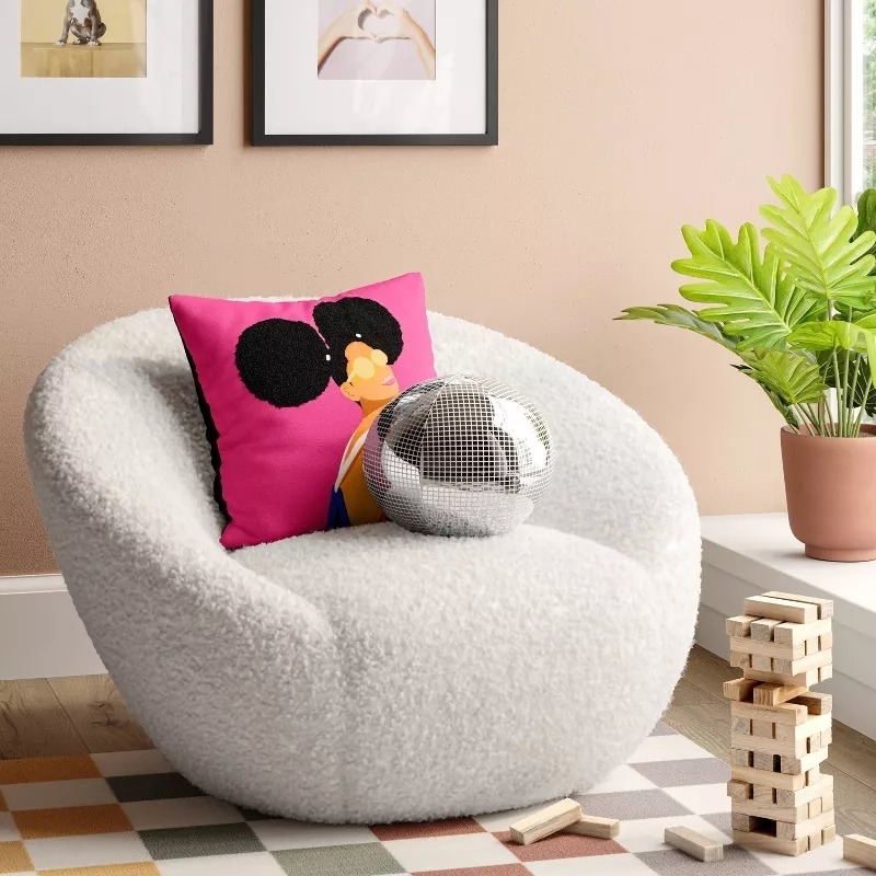 Cozy room with a round chair, disco ball, pink pillow with an abstract face design, plant, and Jenga blocks on a checkered rug