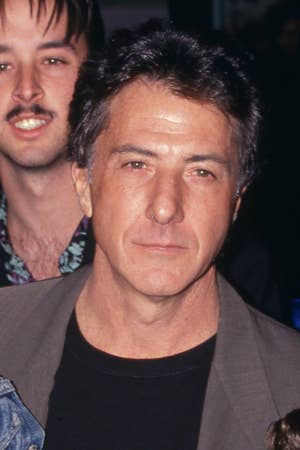 Dustin in a casual blazer and shirt at a public event, with people in the background