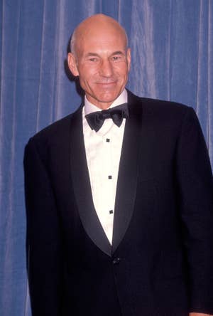 Patrick in a tuxedo and bow tie, smiling in front of a curtain