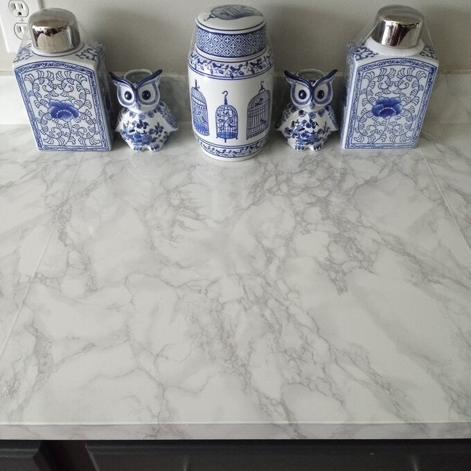 Ceramic jars and decorative owl figurines with intricate patterns displayed on a marble-like countertop