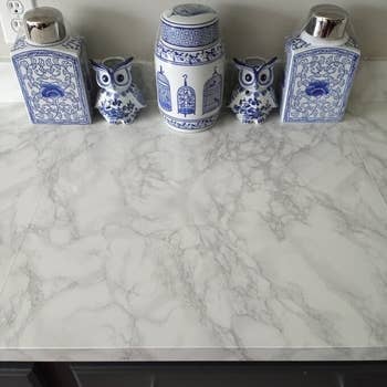 Ceramic jars and decorative owl figurines with intricate patterns displayed on a marble-like countertop
