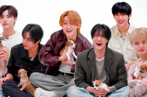 Group of six people sitting with small puppies, smiling and casually dressed