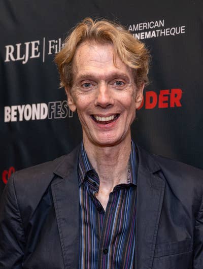Doug on a red carpet in a dark suit and striped shirt at an event for Beyond Fest