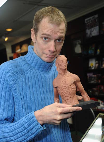Doug in a textured sweater holds a detailed creature sculpture