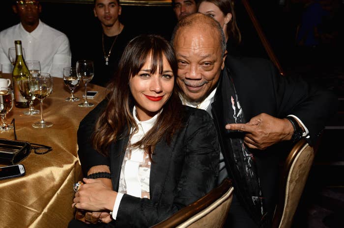 Rashida and Quincy Jones pose at a formal event, Rashida wearing a chic blazer and Quincy pointing playfully at her and smiling