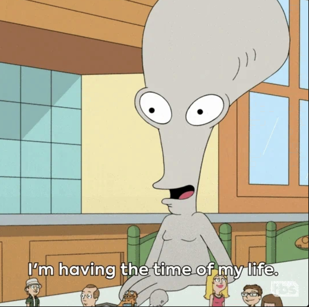 Animated character Roger from "American Dad" at a table, smiling with mouth open, saying, "I'm having the time of my life."