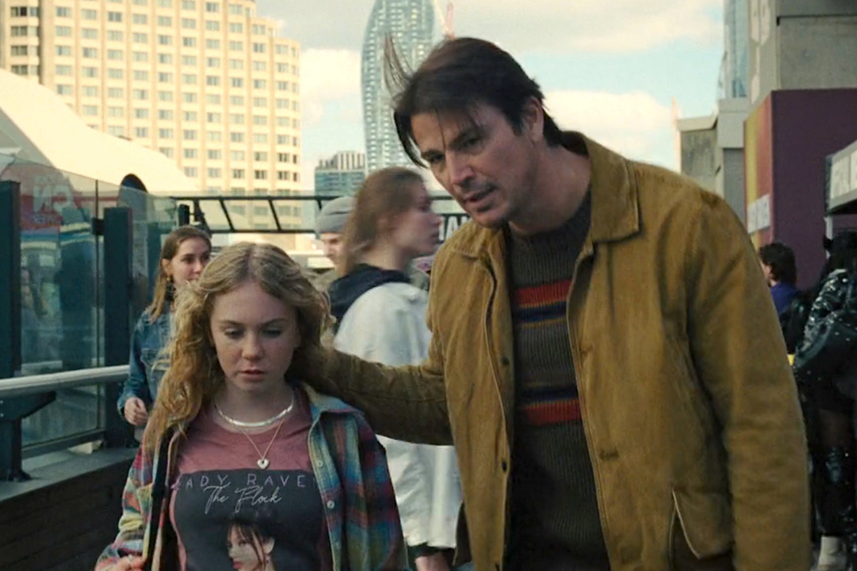 A man and a young girl walk through a busy urban area