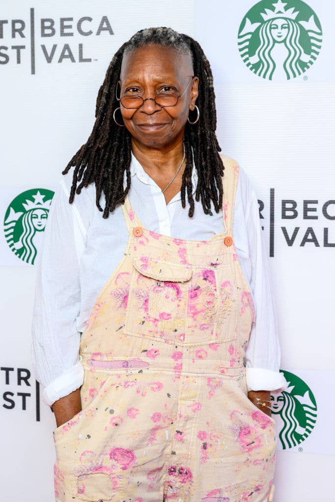 Person in casual, paint-splattered overalls and a white shirt at a Tribeca event backdrop