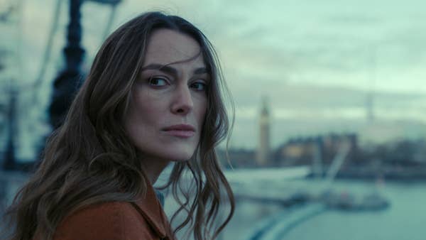 Person gazes thoughtfully near a blurred cityscape, with iconic landmarks visible in the background