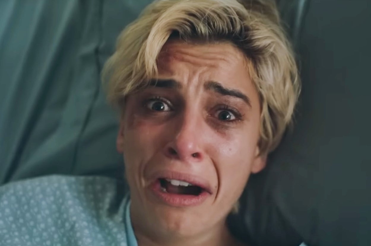 A person with short hair lies in a hospital bed, appearing distressed and tearful, conveying a powerful emotional moment