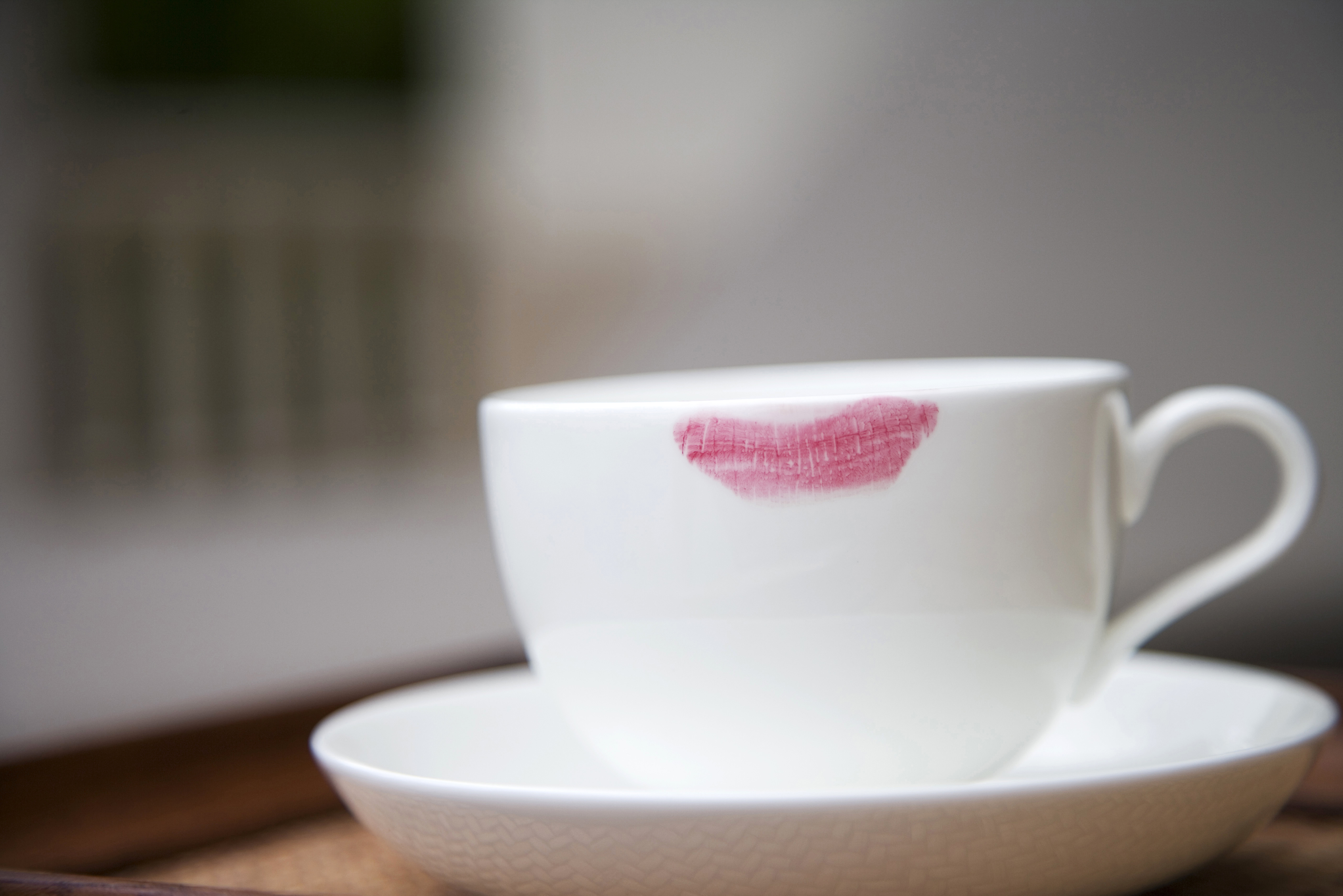 White cup and saucer with a lipstick stain on the rim.