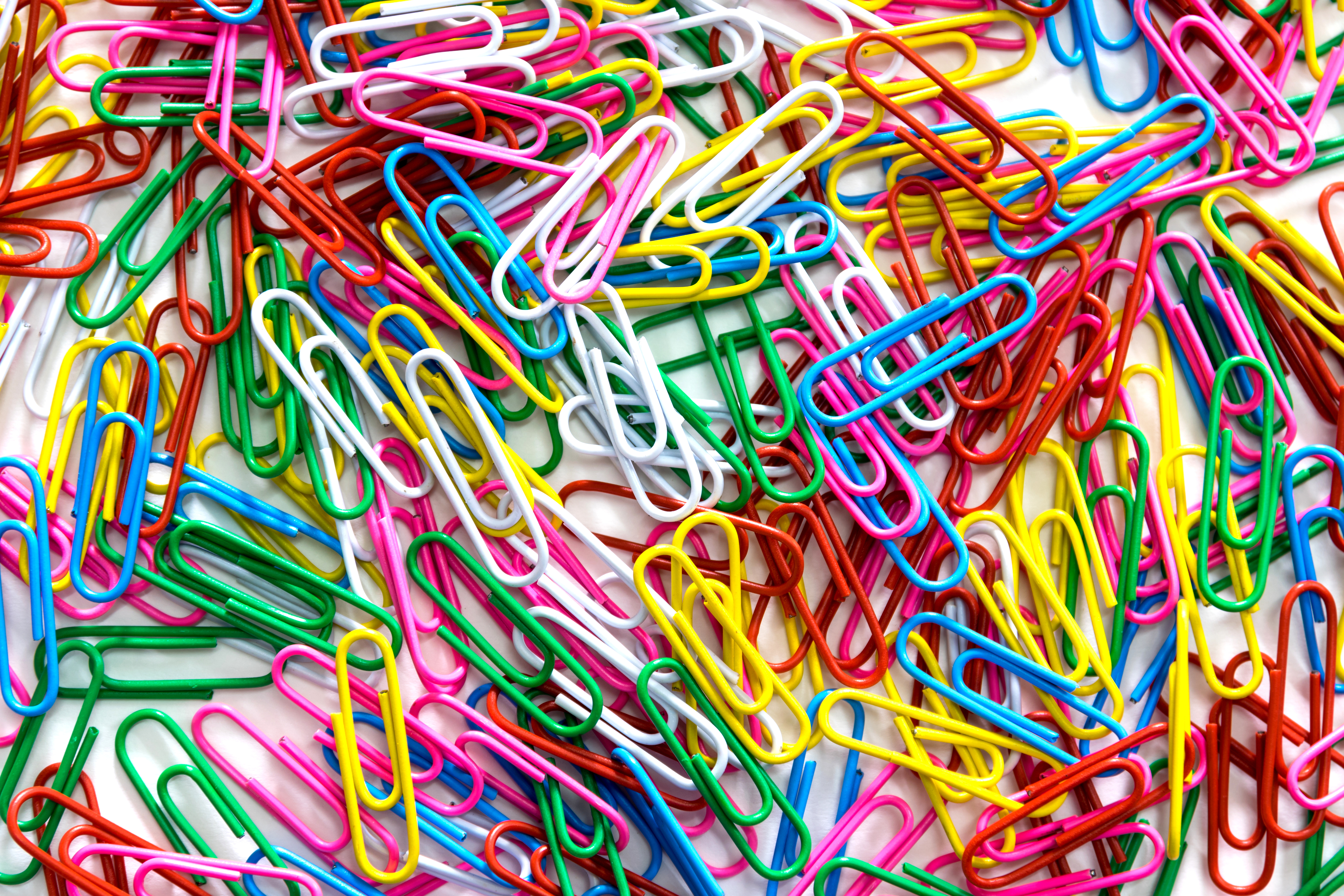 A pile of assorted paperclips in various shapes and sizes scattered randomly.