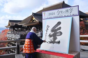 ２０２４年の「今年の漢字」に選ばれた「金」を揮毫（きごう）する清水寺の森清範貫主＝１２日、京都市東山区（時事通信）