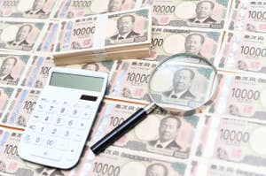 電卓と虫眼鏡が置かれた多くの10000円札。