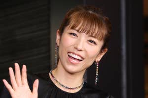 若槻千夏が黒のドレスを着て、笑顔で両手を挙げている。
