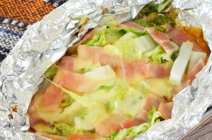 ホイルに包まれた白菜とベーコンの蒸し料理。薄くスライスされ、チーズが溶けている。