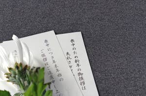 テキストのあるカードが重なり、白い花が添えられています。