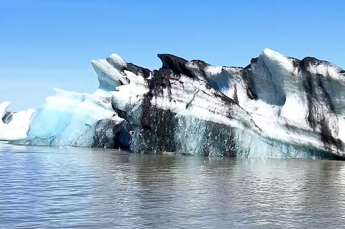 氷河が水面に浮かび、青空が広がる静かな風景。