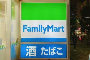 ファミリーマートの看板が夜の街頭に映る。下部に「酒 たばこ」と表示。