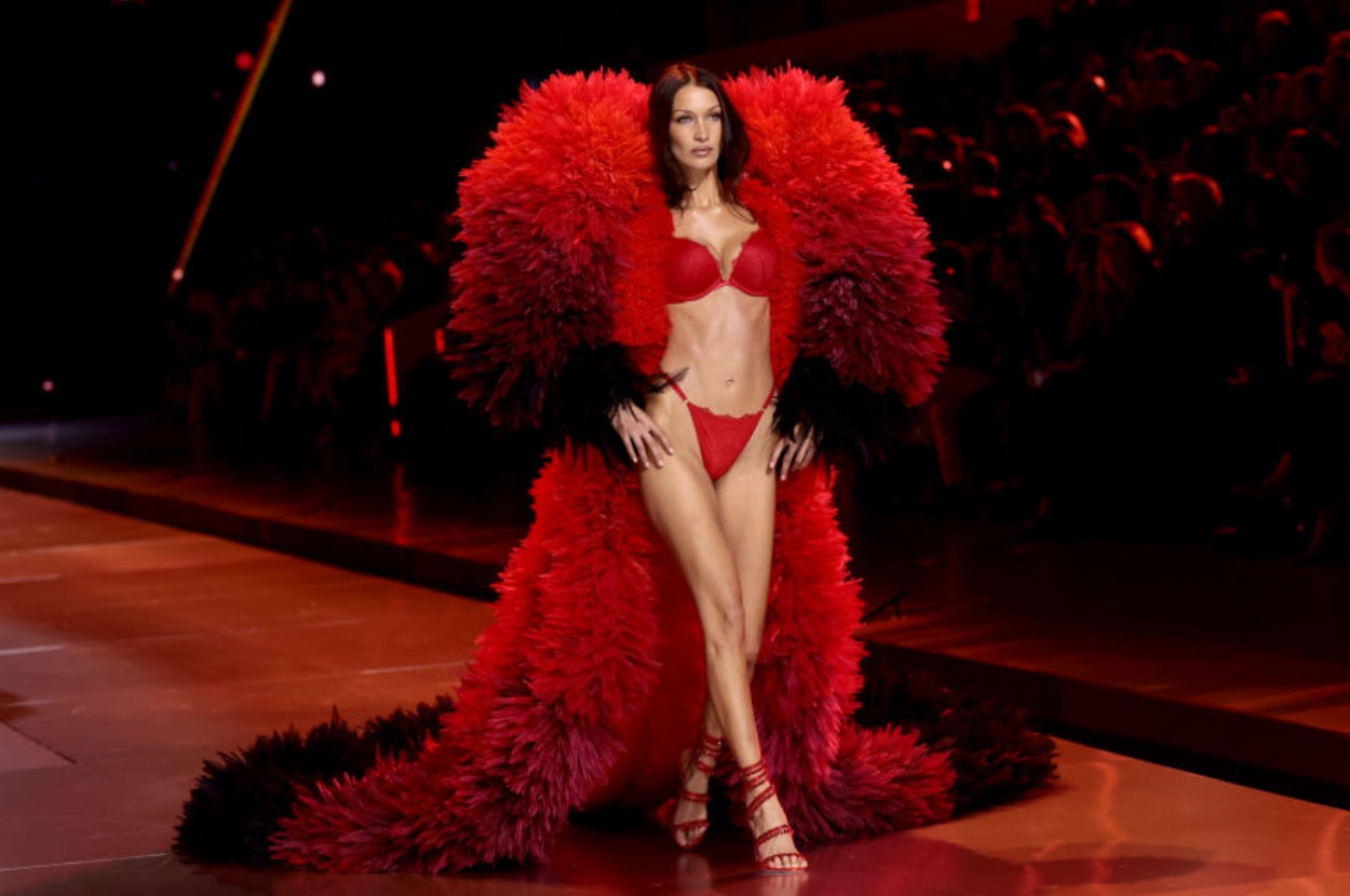 Model on runway wearing dramatic feathered gown and lingerie set, showcasing high fashion style