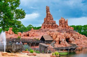 Theme park's Big Thunder Mountain Railroad, featuring rugged rock formations, wooden walkways, and visitors enjoying the scenic attraction