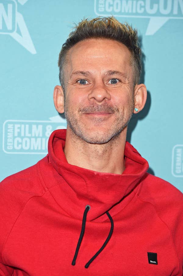 Dominic smiling in a casual hoodie at a film and comic convention event backdrop