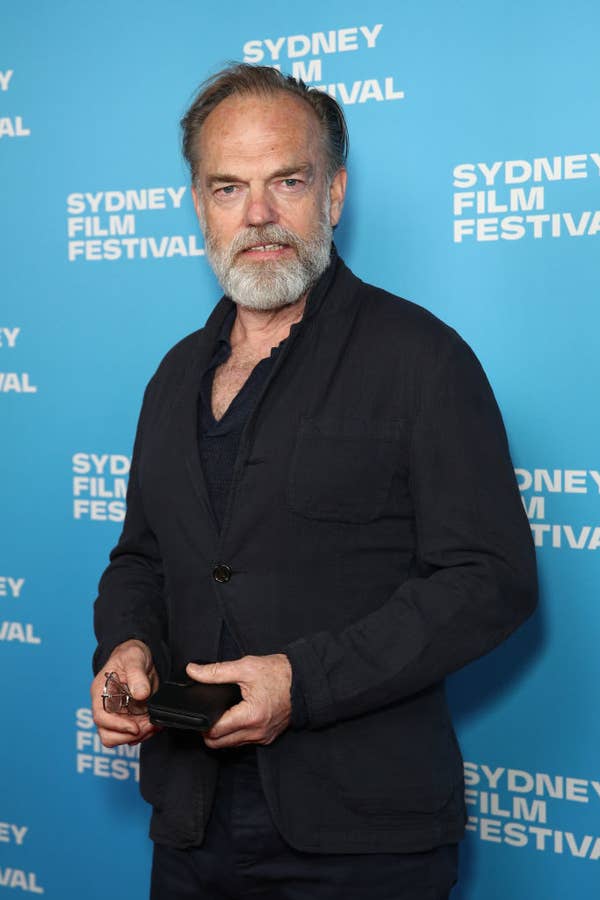 Richard in a dark blazer stands at the Sydney Film Festival backdrop., he is holding glasses