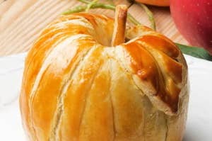 りんごの形をしたパイ。パイ生地に焼き目がついている。背景にりんごが見える。