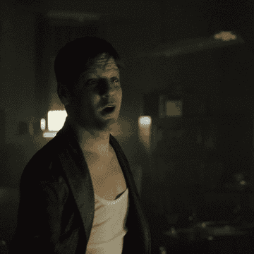 Person in dimly lit room wearing casual clothes, gesturing while speaking energetically