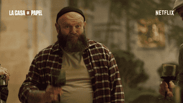 Man with beard and plaid shirt toasting with others with green glasses. &quot;La Casa de Papel&quot; and &quot;Netflix&quot; logos