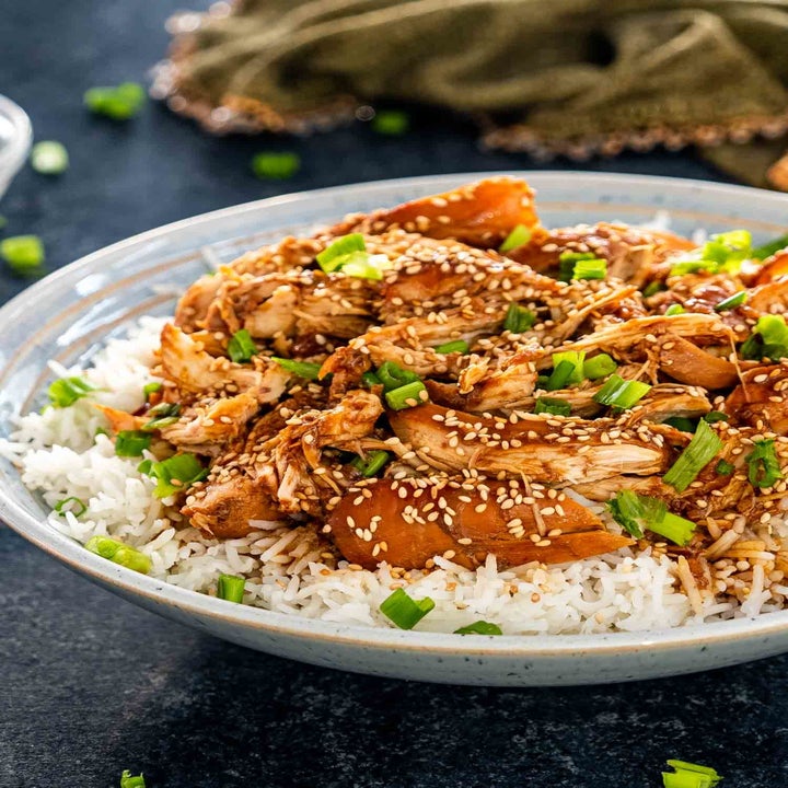 Bowl of rice topped with shredded chicken, sesame seeds, and chopped green onions