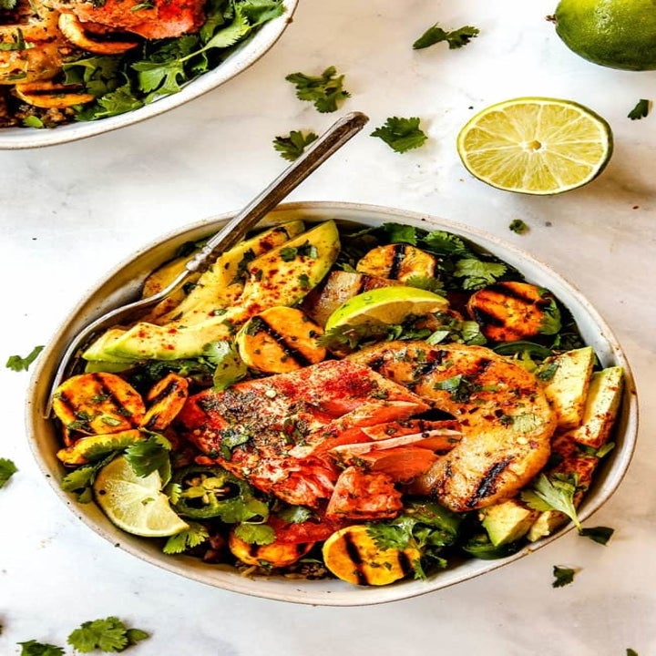 Bowl of grilled shrimp, avocado, and vegetables with lime and herbs, served on a plate