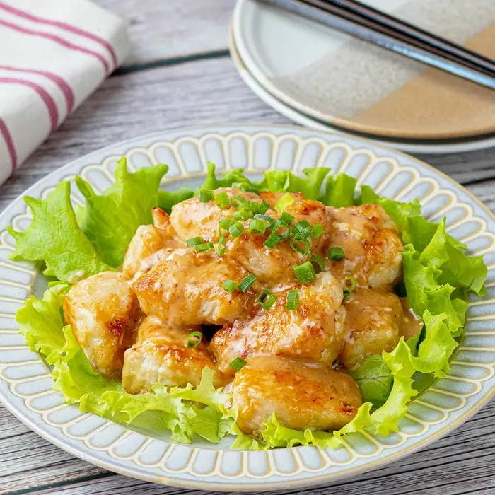 レタスの上に盛られたクリーミーなチキン料理。刻んだネギが飾られている。