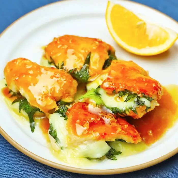 お皿にチーズとハーブが入った焼き前菜が並び、レモンが添えられています。