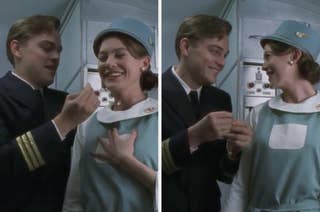 Two people in vintage airline uniforms are smiling and exchanging an object in an airplane interior