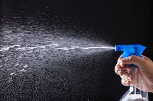 スプレーボトルを押す手から水が霧状に噴射されている様子。