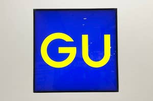Sign displaying bold letters "GU" on a bright background