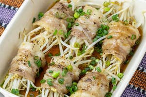 料理の写真。肉巻きもやしがトレイに並べられ、ねぎがトッピングされている。