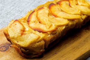 木のまな板の上にあるスライスしたリンゴがトッピングされた焼き菓子。